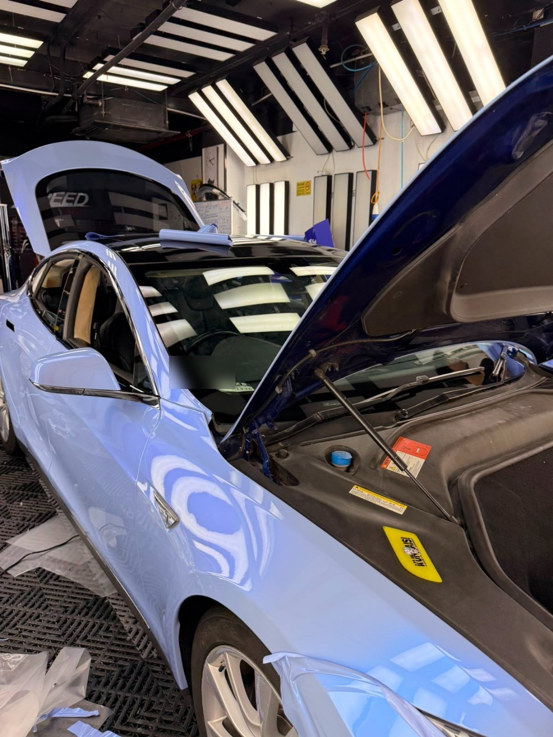 Tesla Model S 施工中，引擎蓋掀開，師傅裁膜貼膜進行中