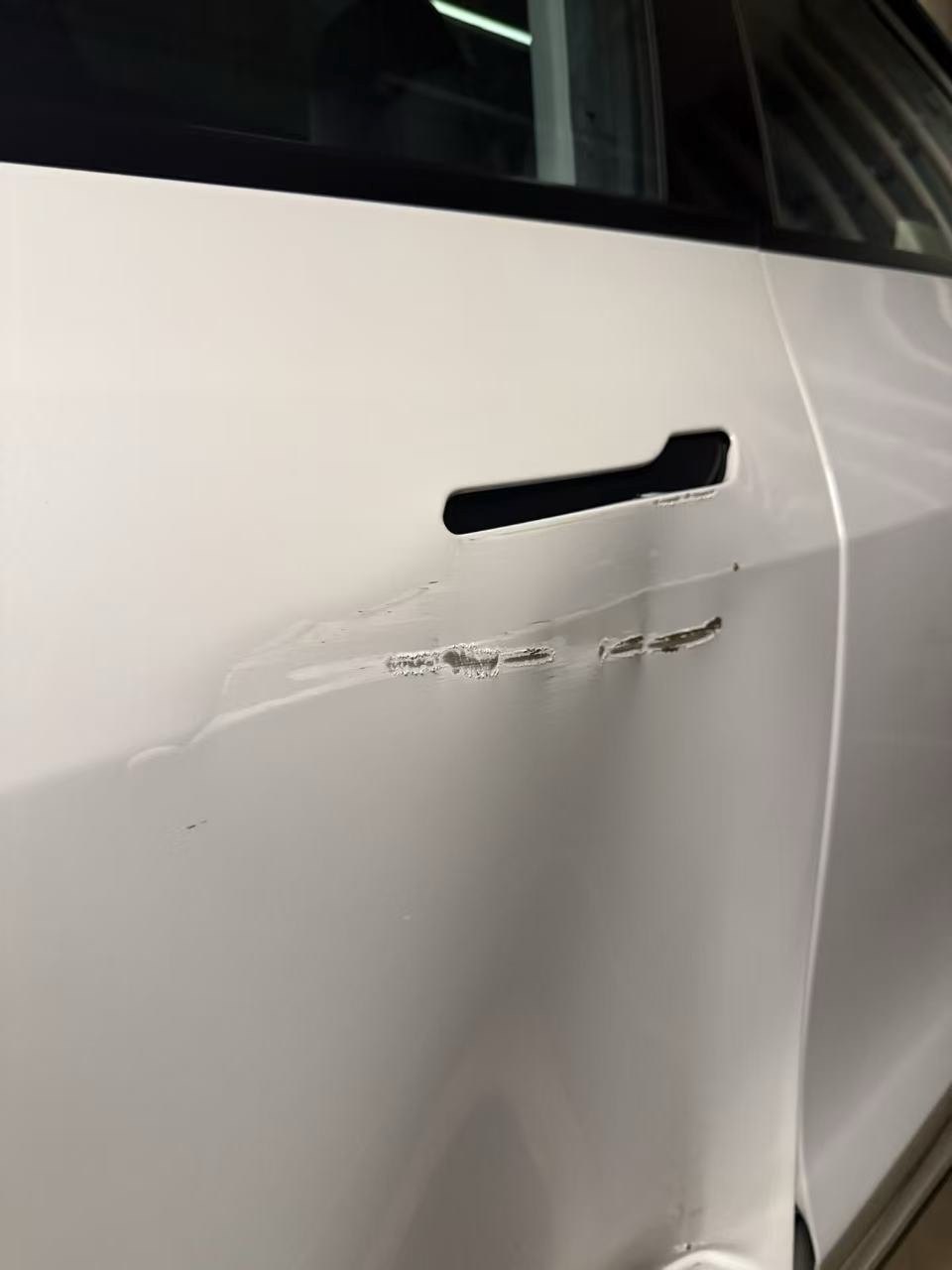 Tesla Model Y 後門深傷特寫，可見底漆同金屬層