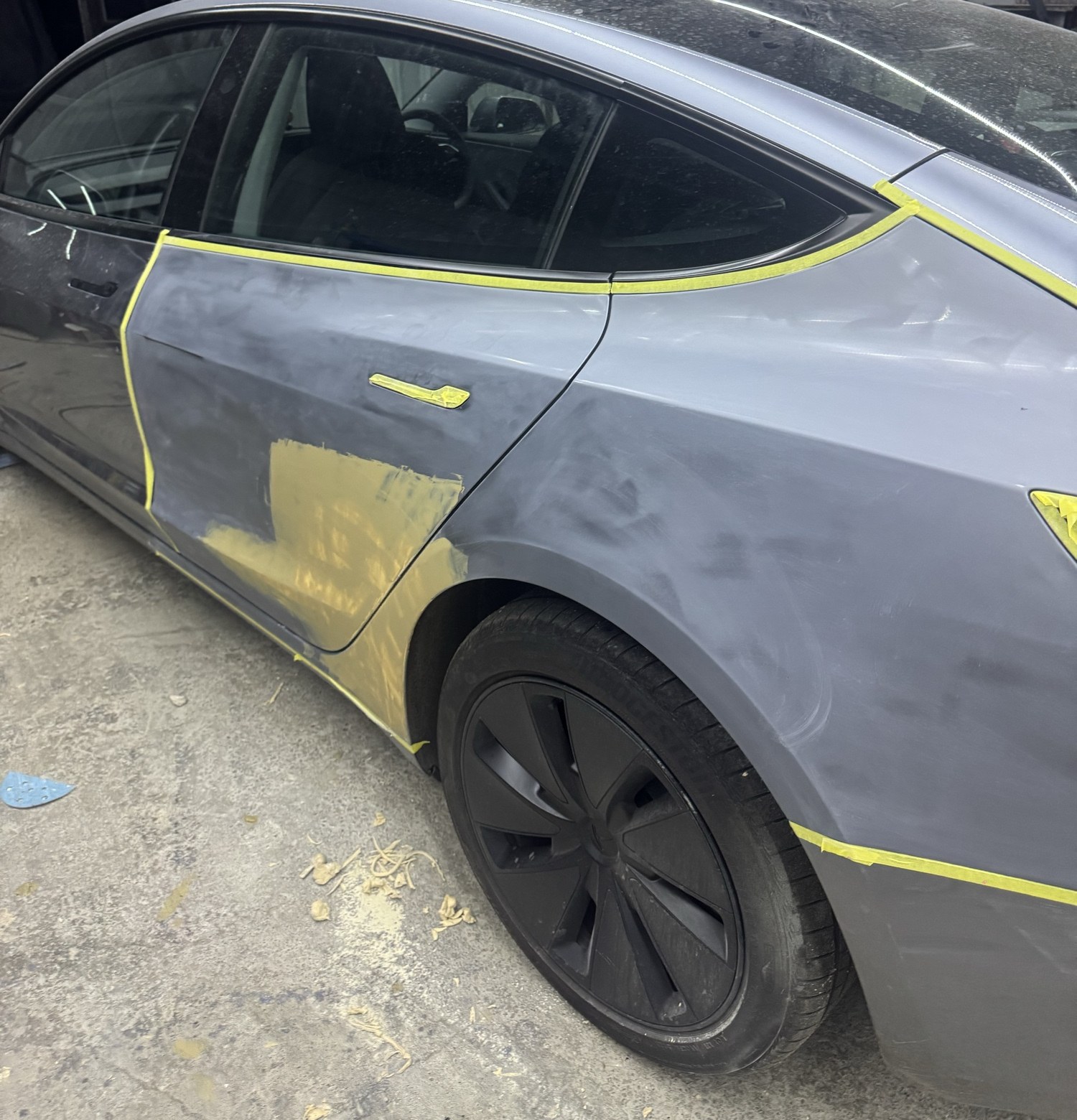 Tesla Model 3 後門刮花見底色，車身用黃色遮蔽膠紙劃出處理範圍