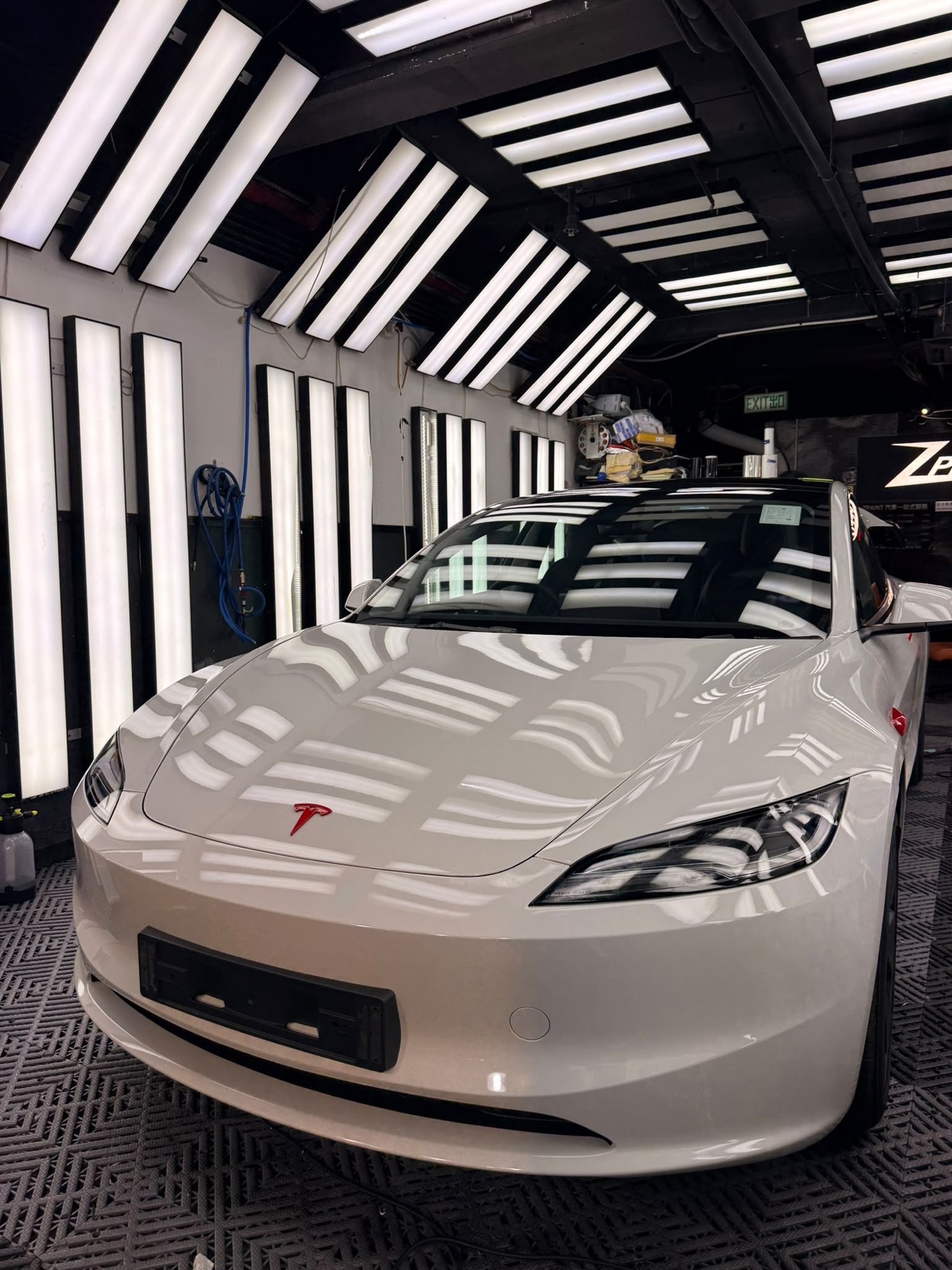 Tesla Model 3 全車改色包膜完成後另一角度，珍珠白車身在燈光下鏡面反光